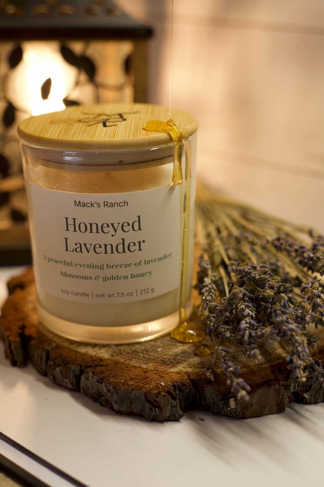 Mack's Ranch Honeyed Lavender candle on a wooden coaster with lavender flowers.